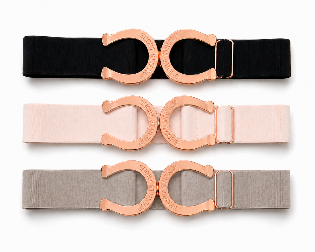 Three elastic waist belts with large horseshoe-shaped rose gold buckles, shown in black, blush pink, and light gray on a white background.