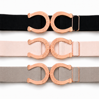 Three elastic waist belts with large horseshoe-shaped rose gold buckles, shown in black, blush pink, and light gray on a white background.